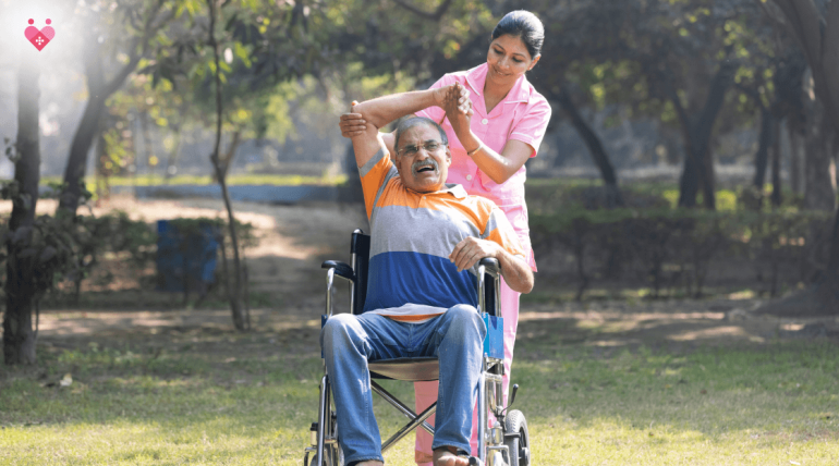 Caregiver helping elderly man in wheelchair with physiotherapy exercise outdoors