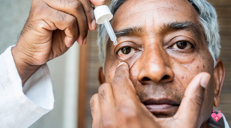 An older man carefully administering medicated eye drops into his lower eyelid to manage eye pressure.
